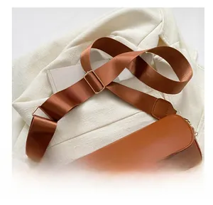 Détail de la large bandoulière en nylon sur un sac selle en similicuir marron chic