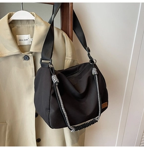 Detail of black canvas tote bag with woven handles next to a trench coat