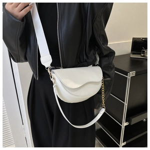 Gros plan d'un sac besace blanc avec bandoulière tissée et chaîne dorée sur mannequin