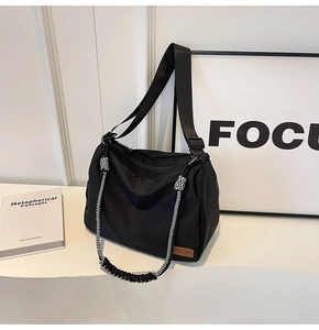 Detail of large black canvas tote bag with woven wave pattern handle and wide strap