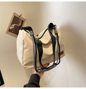 Detail of beige canvas tote with black woven rope handle and brown leather logo tag