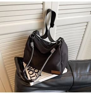 Close-up of minimalist black nylon tote bag with woven rope detail and leather logo patch