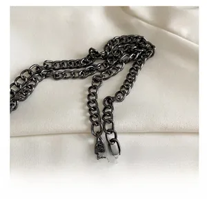 Close-up of premium dark gunmetal chain strap with high-gloss finish on textured fabric