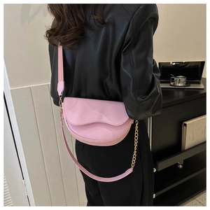 Sac selle demi-lune rose avec rabat ondulé et bandoulière tissée sur veste noire