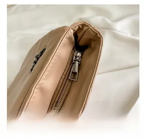 Detail of smooth metal zipper and beige quilted leather texture on crossbody bag