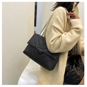 Detail of black V-quilted shoulder bag with matching metal chain and secure lock