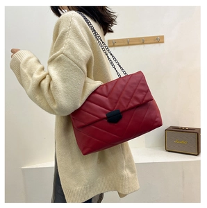 Close-up of wine red quilted leather shoulder bag with chic black metal chain strap