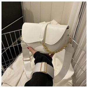 Détail du sac selle blanc avec chaîne dorée et bandoulière large en tissu