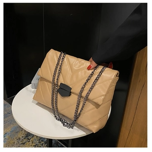 Macro detail of beige quilted PU leather shoulder bag with chic black chain strap