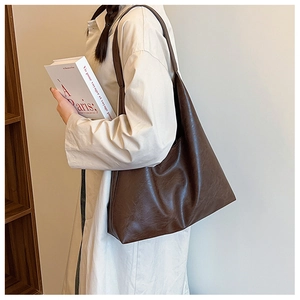 Détail d'un grand sac cabas marron en similicuir vintage porté à l'épaule