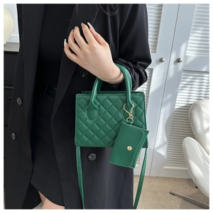 Detail of green quilted crossbody bag with matching coin purse and golden hardware