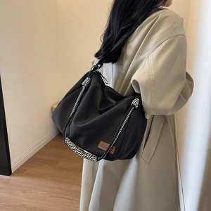 Black canvas tote bag for women with woven handle shown on shoulder for daily commute