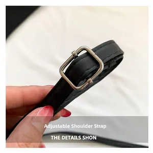 Detail of adjustable black leather strap with a silver metal buckle and stitching