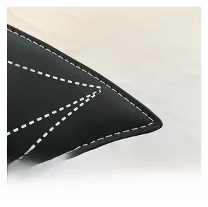Detailed macro shot of black leather handbag with white contrast stitching and geometric seams