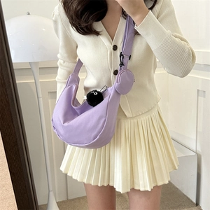 Purple nylon crescent crossbody bag with small round coin purse and plush charm accessory
