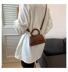 Close-up of a brown litchi pattern leather crossbody bag shown on a person's back