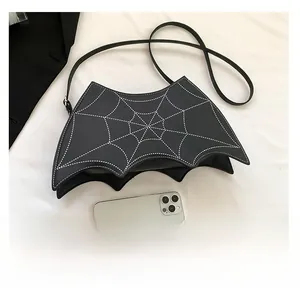 Detail view of black bat-shaped bag with spider web stitching and size reference phone