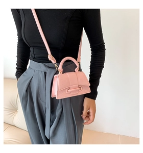 Detail of pink hourglass crossbody bag with woven texture and top handle on a model