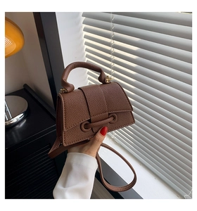 Brown lychee leather crossbody bag with top handle and decorative buckle detail