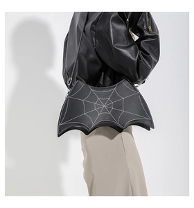Detail of bat-shaped crossbody bag featuring white spider web stitching on black leather