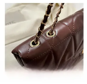 Detail of dark brown quilted leather bag featuring gold grommets and chain strap link