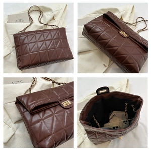 Detail of dark brown quilted bag showing chain strap, gold clasp and spacious interior
