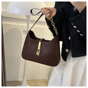 Macro shot of dark brown leather underarm bag featuring vintage gold lock and chain strap