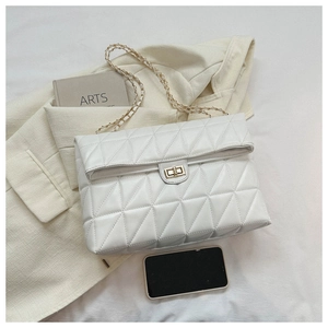 Close-up of white quilted shoulder bag with gold chain strap and turn-lock closure