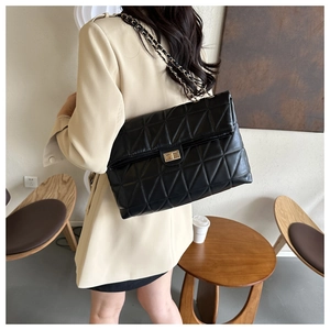 Detail of the black quilted shoulder bag featuring gold twist lock and leather chain strap