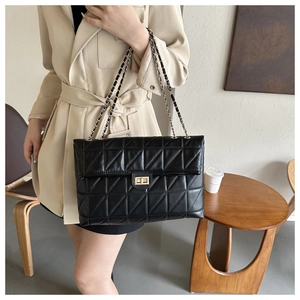 Close-up of black quilted shoulder bag featuring gold twist lock and leather chain strap