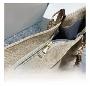 Close-up of smooth golden metal zipper and brown leather handle on a suede tote bag