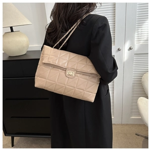 Detail of beige quilted shoulder bag with gold chain strap and metal twist lock