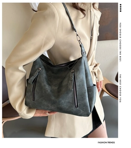 Détail d'un sac cabas gris vintage avec zips fonctionnels sur un trench-coat beige