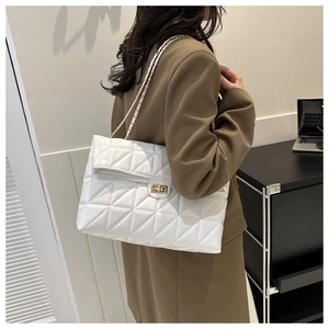 Detailed view of white quilted shoulder bag with chain strap and metallic buckle lock