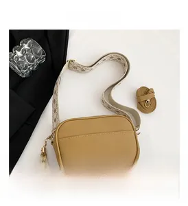 Detail of khaki pebbled leather crossbody bag with geometric wide strap and tassel