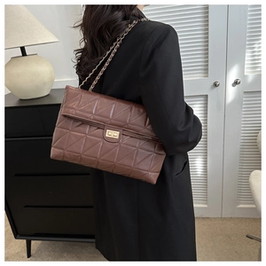 Detail of dark brown quilted bag with triangular stitching and gold metal twist lock