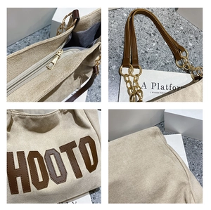 Detail view of large tote bag showing brown HOOTO embroidery and metal chain hardware