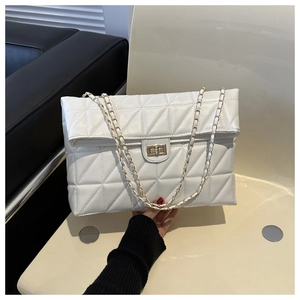 Close-up of white quilted shoulder bag with gold chain strap and turn-lock closure