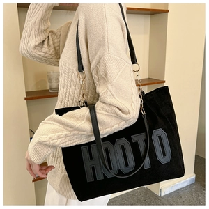 Detail of black tote bag with HOOTO lettering and metal chain leather shoulder strap