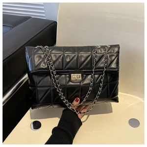 Detail of black quilted leather texture with gold square metal twist lock on a flap bag