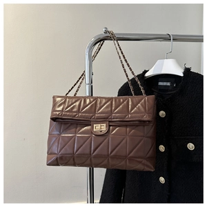 Detail of quilted brown PU leather bag with gold turn-lock and chain strap on hanger