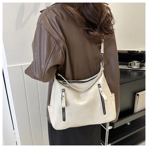 Détail du sac hobo blanc cassé avec fermetures éclair verticales et poches latérales sur modèle