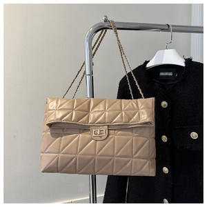 Close-up of beige quilted bag featuring triangular stitching and metal turn-lock closure