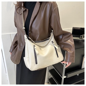 Detailansicht der cremefarbenen Ledertasche mit funktionalen Doppel-Reißverschlüssen