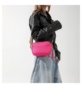 Detail of fuchsia leather crossbody bag with colorful patterned wide strap and tassel