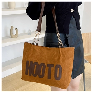 Detail of brown suede tote bag with HOOTO logo and gold metal chain shoulder strap