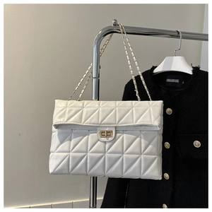 Detail of white quilted handbag with diamond pattern, chain strap, and metal turn-lock