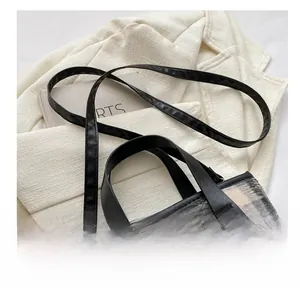 Detail of adjustable leather strap and metal buckle on checkered wool tote bag
