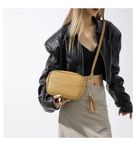 Detail view of mustard yellow PU leather camera bag with fringe and adjustable strap