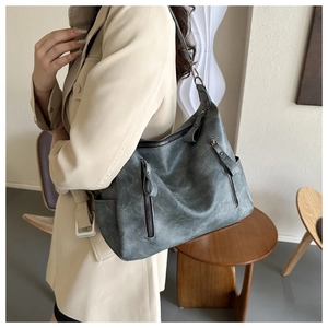 Gros plan d'un grand sac hobo vintage en similicuir gris-vert porté par un mannequin